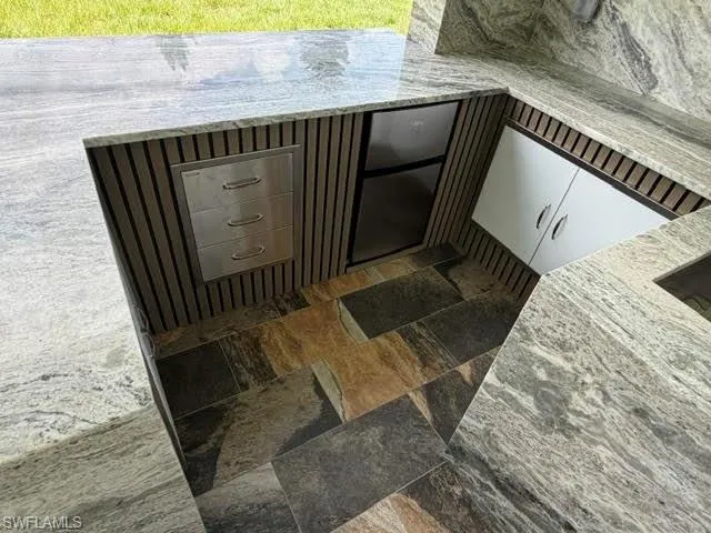 Outdoor kitchen featuring a built-in stainless steel refrigerator, white cabinetry, and stainless steel drawer storage
