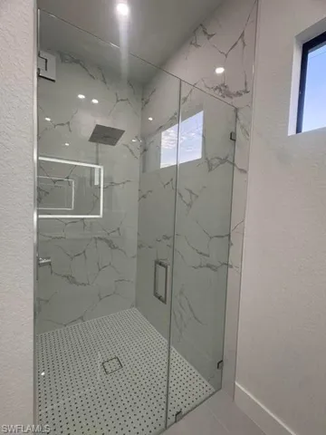 Walk-in shower with clear glass enclosure and marble-look wall tiling