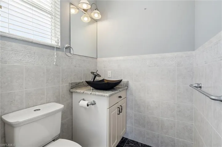 Bathroom with tile walls, vanity, and toilet