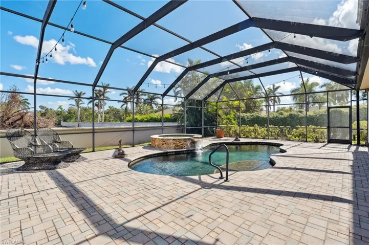 View of swimming pool featuring a lanai, pool water feature, an in ground hot tub, and a patio area