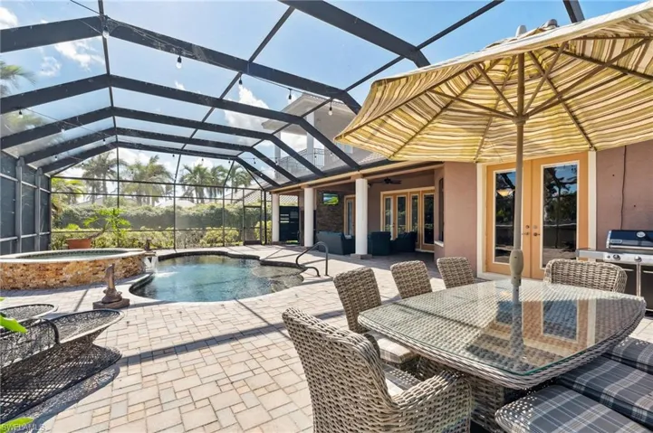 View of swimming pool with glass enclosure, french doors, a patio, and an in ground hot tub