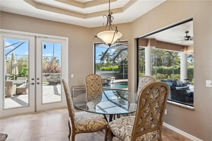 Tiled dining area featuring french doors, plenty of natural light, ceiling fan, and a raised ceiling