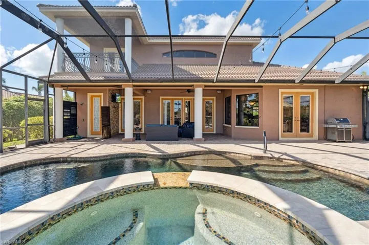 View of pool with grilling area, an in ground hot tub, a patio area, glass enclosure, and ceiling fan