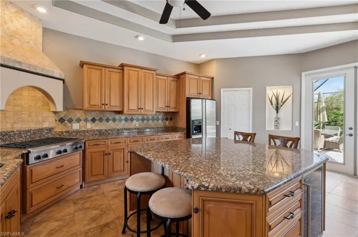 Kitchen featuring a kitchen bar, stainless steel appliances, dark stone counters, tasteful backsplash, and a kitchen island