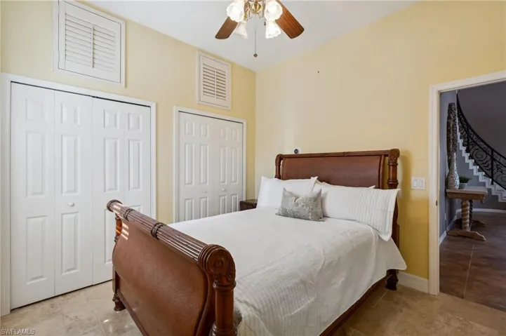 Bedroom with multiple closets, ceiling fan, and light tile patterned flooring