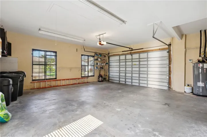 Garage featuring electric water heater and a garage door opener