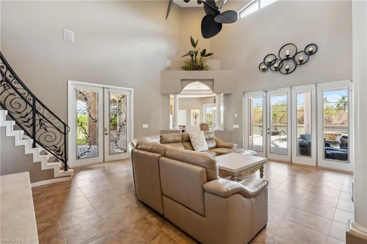 Tiled living room featuring french doors, ornate columns, and a towering ceiling