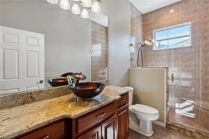Bathroom with tile patterned flooring, vanity, toilet, and a shower with shower door