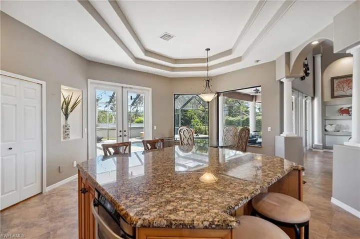 Kitchen featuring ornate columns, dark stone counters, and a kitchen island