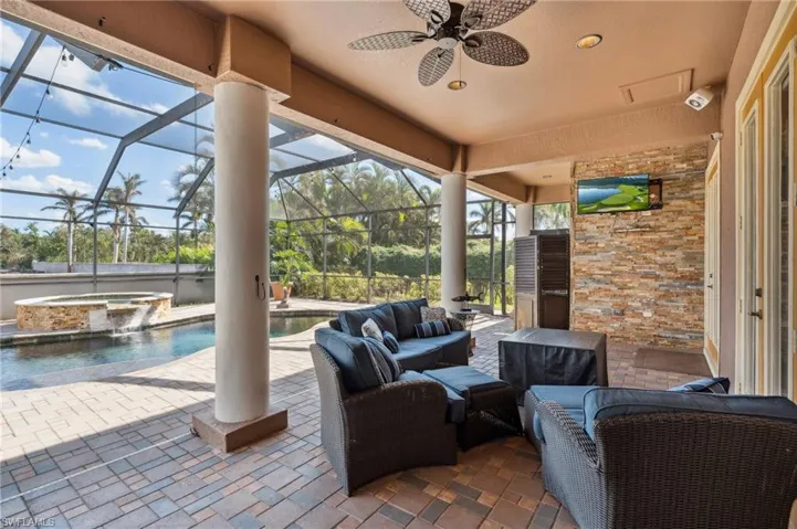 View of patio / terrace featuring a lanai, a swimming pool with hot tub, ceiling fan, and an outdoor hangout area