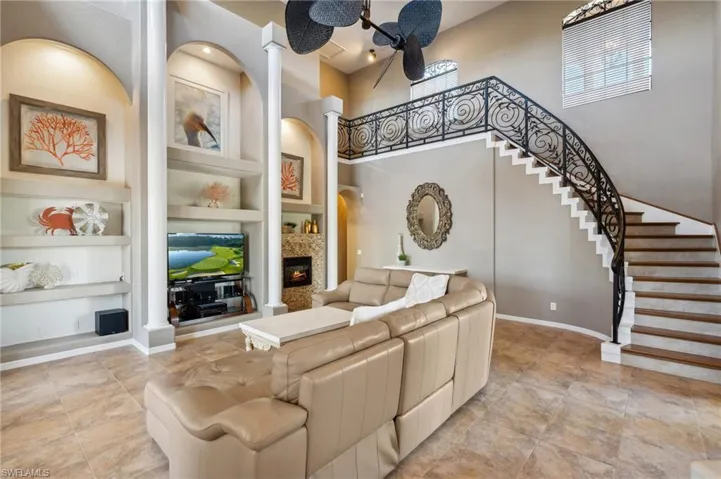 Living room featuring built in shelves, a towering ceiling, and decorative columns
