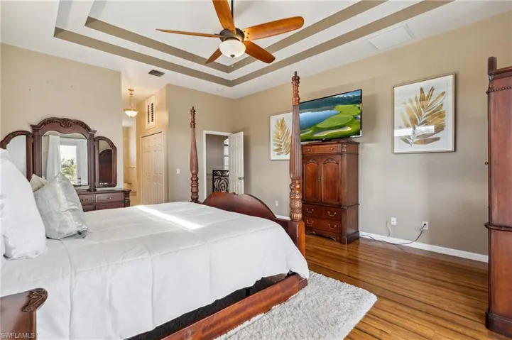 Bedroom featuring a closet, wood-type flooring, ceiling fan, and a raised ceiling