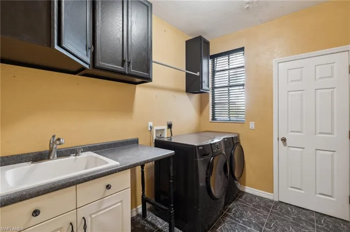 Laundry room with cabinets, washer and dryer, a textured ceiling, and sink