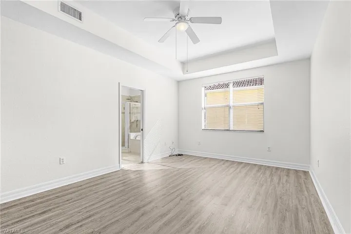 Unfurnished room with wood finished floors, a ceiling fan, and a tray ceiling