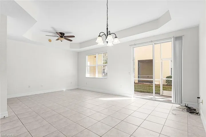 Spare room featuring a raised ceiling, hanging lights, a ceiling fan, and light tile patterned flooring