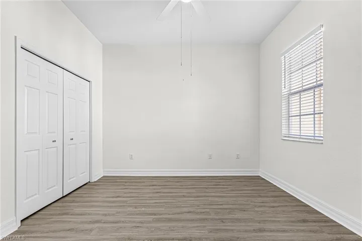 Unfurnished bedroom featuring wood finished floors, a closet, and a ceiling fan