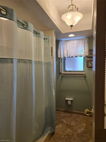 Full bathroom featuring a shower with shower curtain and a textured ceiling