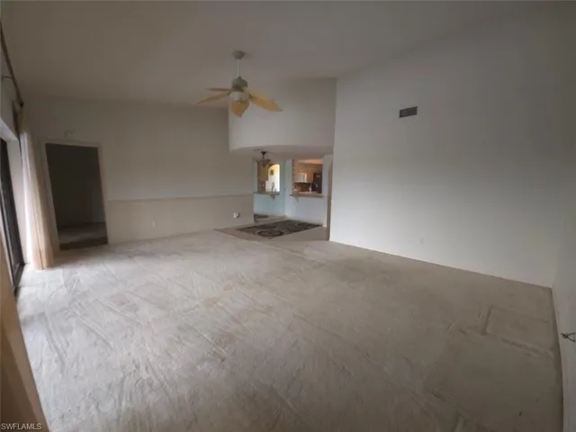 Unfurnished living room featuring carpet flooring and a ceiling fan