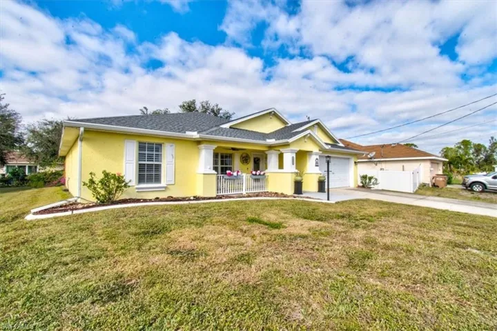 Ranch-style home with covered porch, a garage, and a front lawn