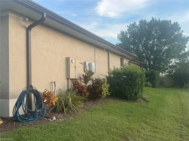 View of side of property featuring stucco siding and a yard