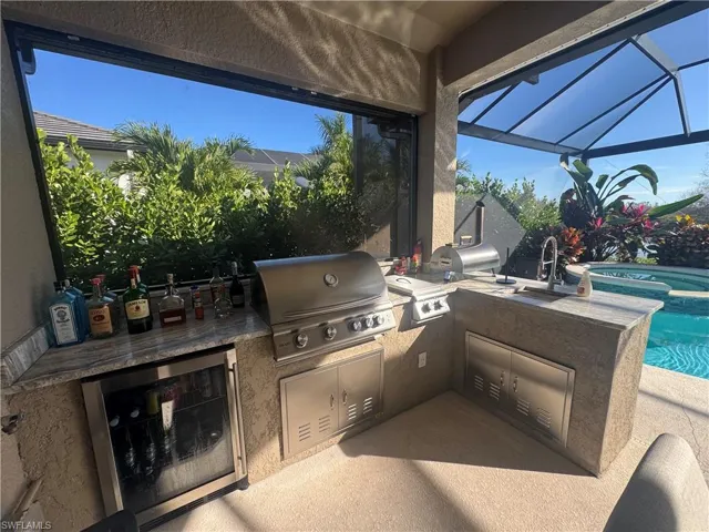 View of patio / terrace featuring a lanai, area for grilling, and a pool with connected hot tub