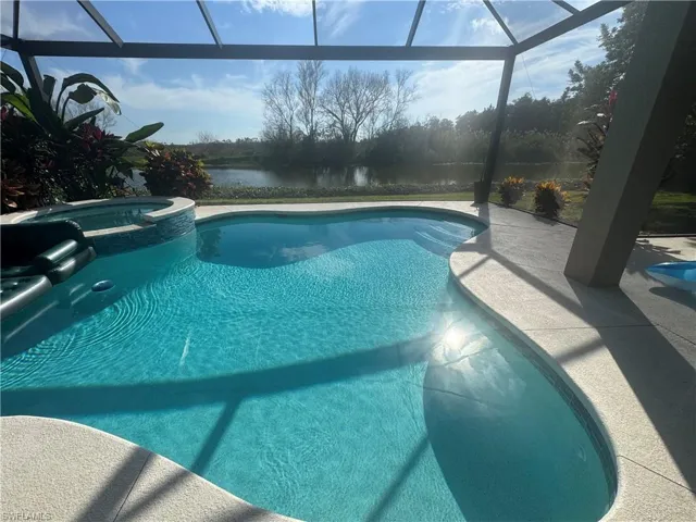 View of pool featuring a lanai, a sunroom, a water view, and a pool with connected hot tub