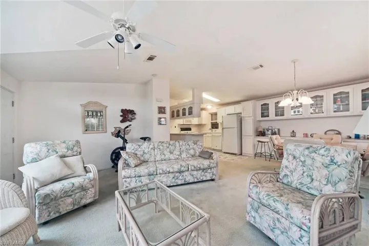 Carpeted living room featuring a chandelier, lofted ceiling, and a ceiling fan