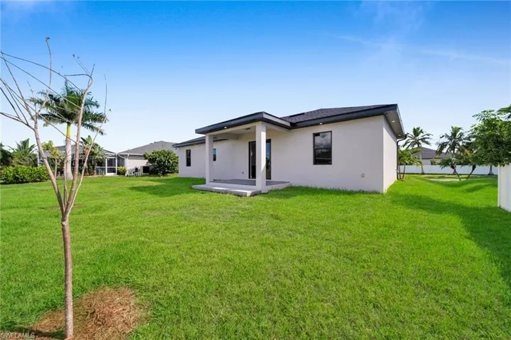 Rear view of property featuring a lawn, stucco siding, and a patio area
