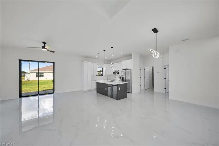 Kitchen featuring open floor plan, white cabinetry, pendant lighting, a kitchen island, and recessed lighting