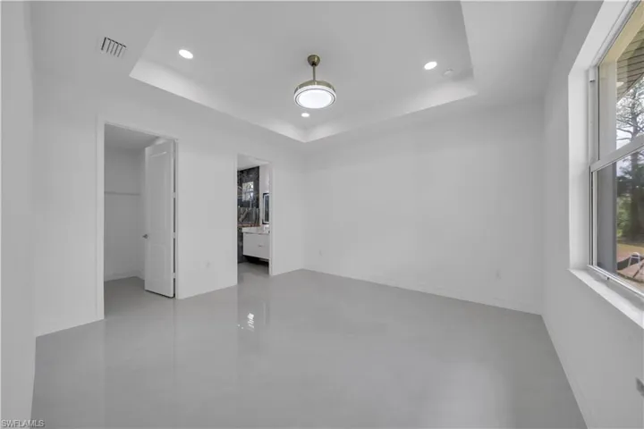 Empty room featuring a tray ceiling, recessed lighting, and baseboards