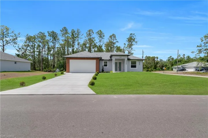 View of front of property with a garage, concrete driveway, a front lawn, and a shingled roof
