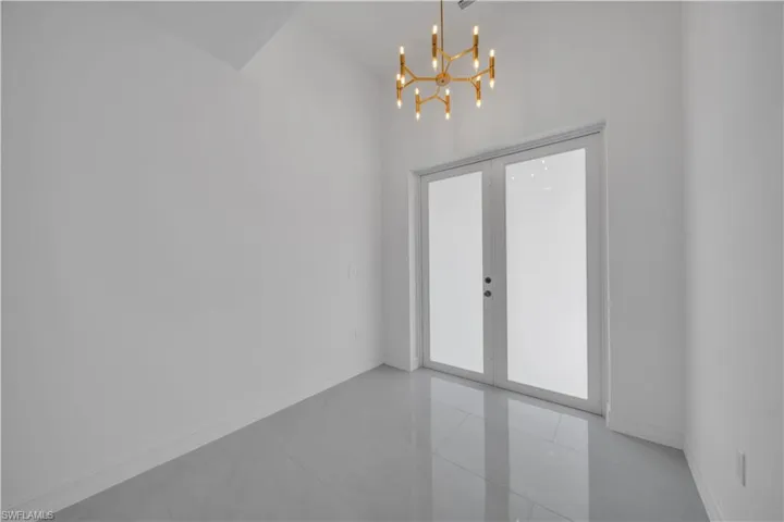 Empty room with baseboards, a chandelier, tile patterned flooring, and french doors