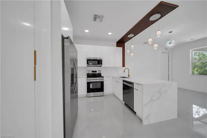 Kitchen featuring stainless steel appliances, modern cabinets, white cabinets, a peninsula, and pendant lighting