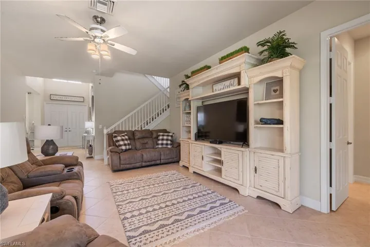 Living room with ceiling fan and light tile patterned flooring