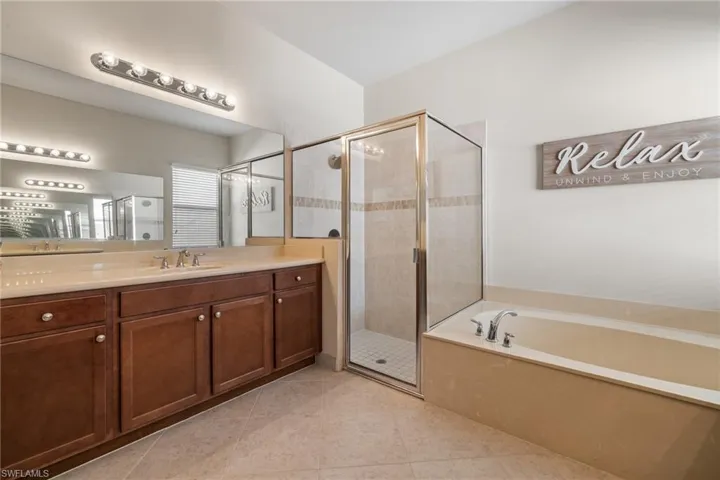 Bathroom featuring tile patterned floors, vanity, and plus walk in shower