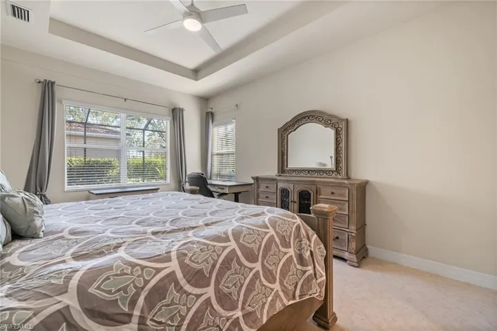 Bedroom with a raised ceiling and ceiling fan