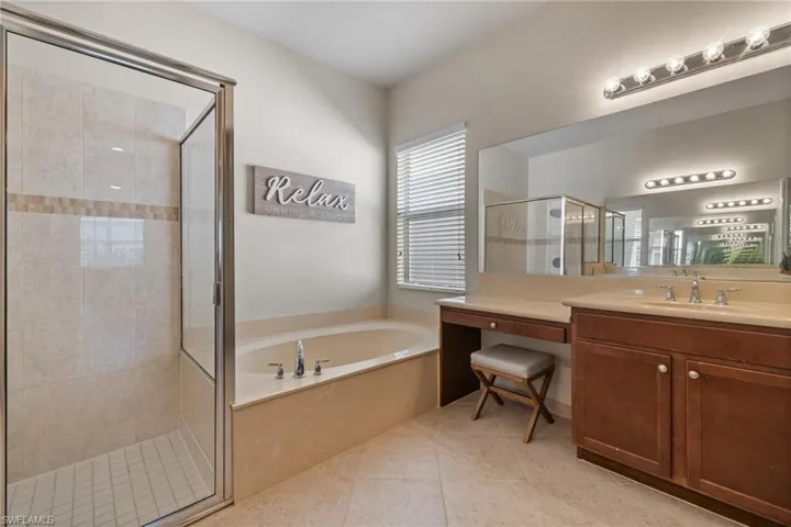 Bathroom featuring tile patterned floors, vanity, and shower with separate bathtub