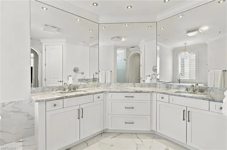 Dual vanity with individual sinks, white cabinetry, integrated mirrors, stone countertops, and recessed lighting