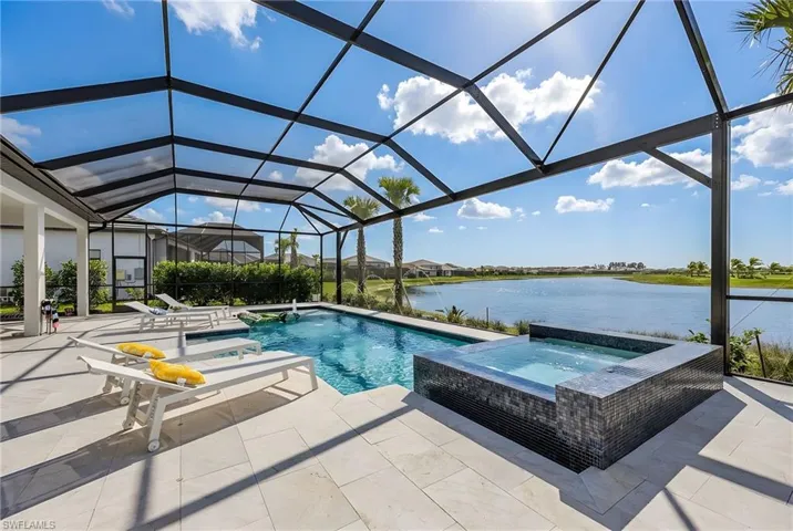 Relaxing pool / spa featuring a sunroom, glass enclosure, a water view, and a patio area