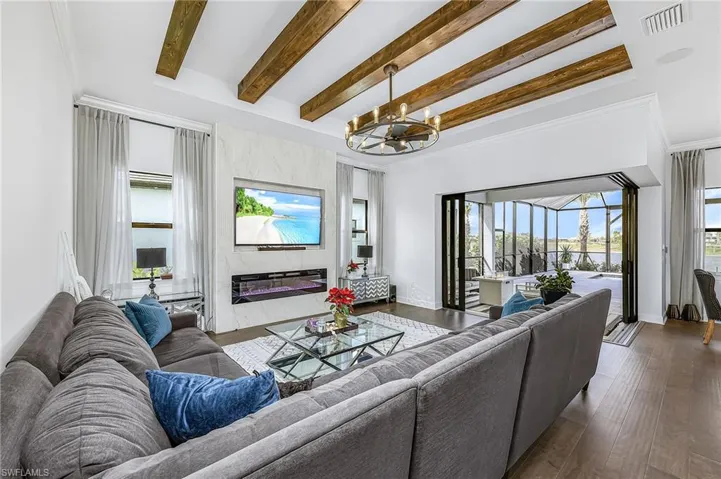 Living area featuring beam ceiling, a premium fireplace, a sunroom, hardwood / wood-style flooring, and ornamental molding