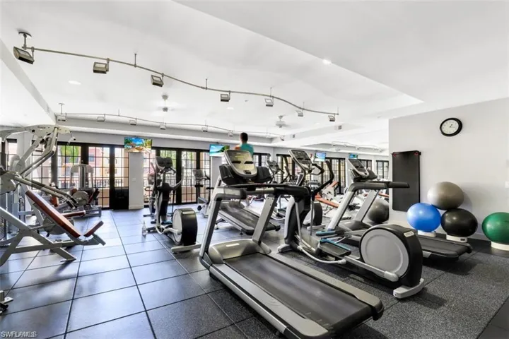 Gym with tile flooring, a tray ceiling, and rail lighting