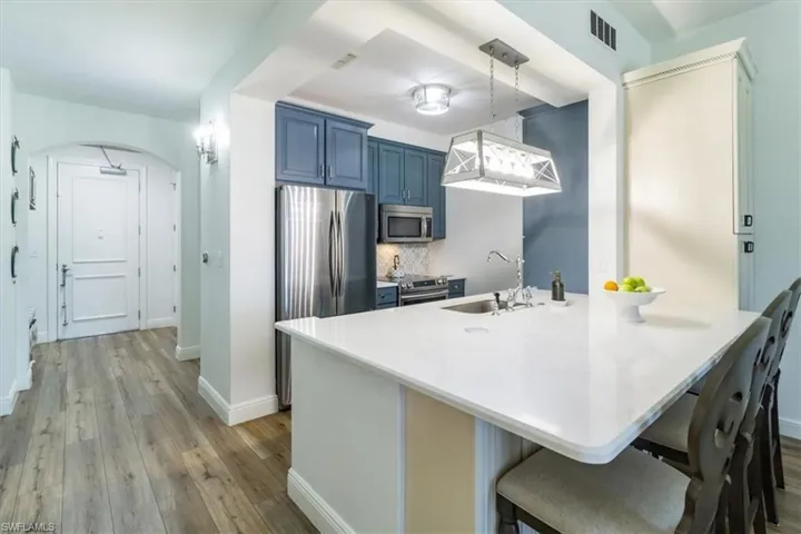 Kitchen featuring light hardwood / wood-style flooring, kitchen peninsula, stainless steel appliances, blue cabinetry, and sink