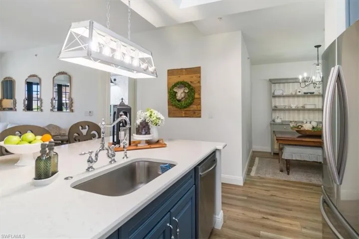 Kitchen with light hardwood / wood-style flooring, a notable chandelier, blue cabinets, appliances with stainless steel finishes, and sink