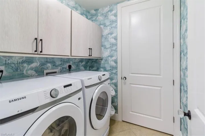 Clothes washing area featuring cabinets, light tile flooring, electric dryer hookup, washer and clothes dryer, and hookup for a washing machine