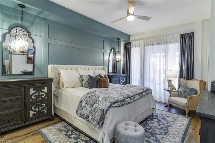 Bedroom with ceiling fan with notable chandelier and hardwood / wood-style flooring
