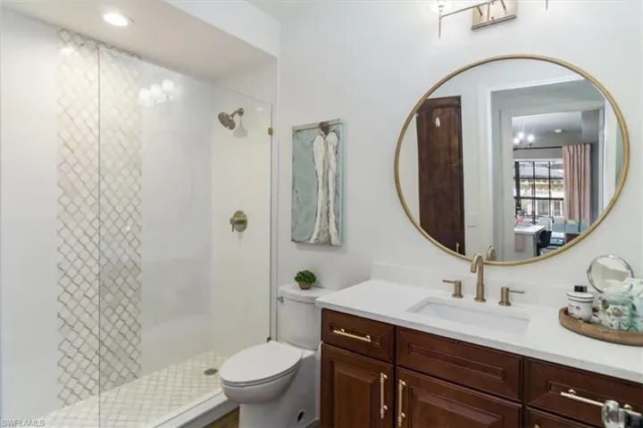 Bathroom featuring a shower with shower door, toilet, and vanity