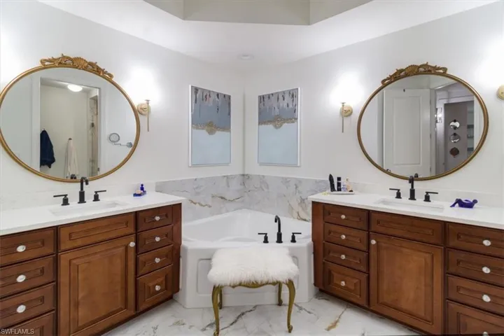 Bathroom featuring tile flooring, dual vanity, and a tub
