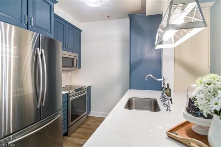 Kitchen featuring stainless steel appliances, blue cabinetry, hardwood / wood-style flooring, and sink