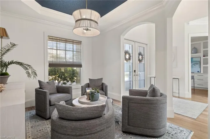 Living room featuring french doors, hardwood / wood-style flooring, ornamental molding, and a raised ceiling