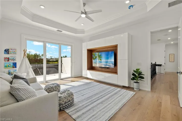 Living room featuring crown molding, a tray ceiling, light wood-type flooring, and ceiling fan